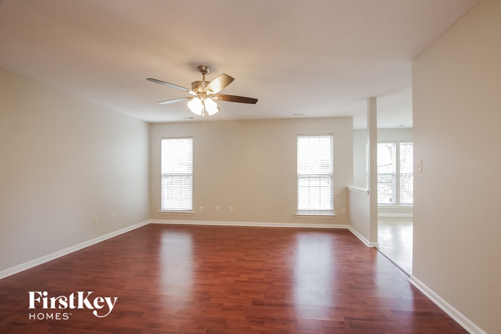 A spacious room with a ceiling fan and wooden flooring.