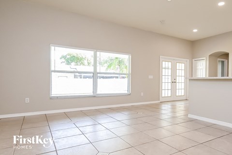 an empty living room with large windows and tiled flooring