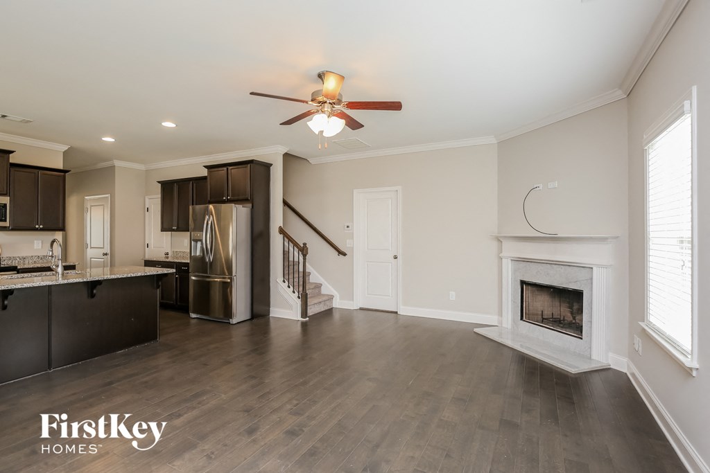 a kitchen and living room with a fireplace and a ceiling fan