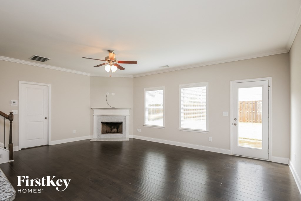 an empty living room with a ceiling fan and a fireplace