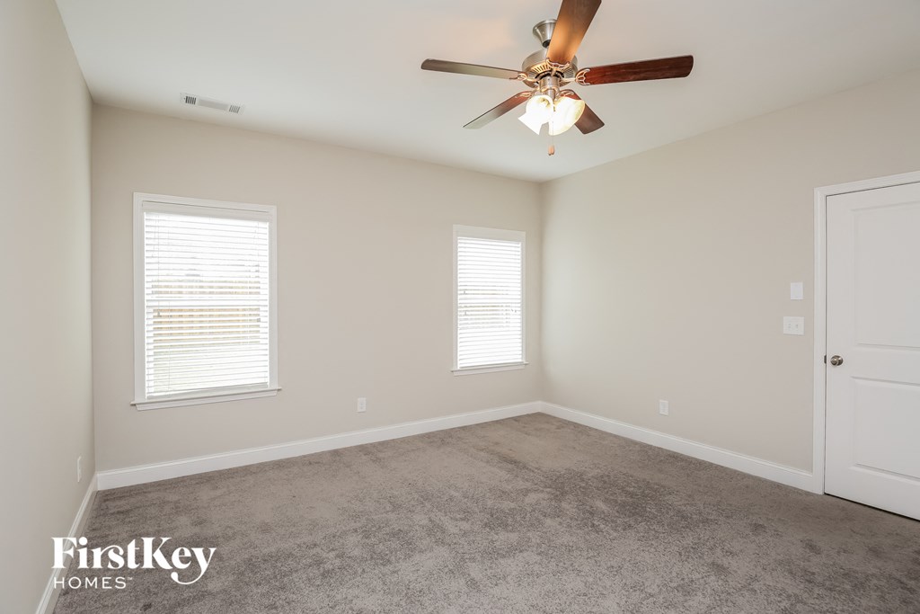 a carpeted room with a ceiling fan and two windows