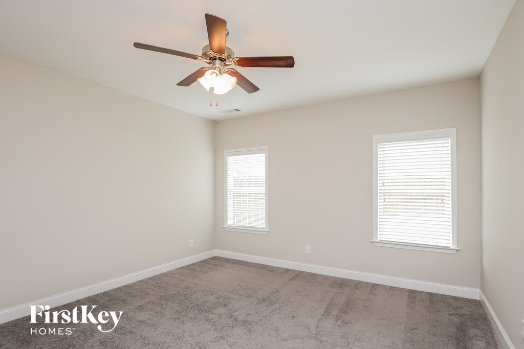 a living room with a ceiling fan and a concrete floor