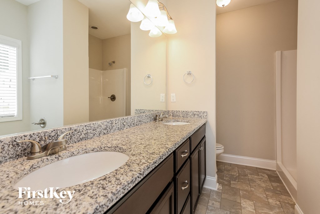the master bathroom has dual sinks and a large mirror