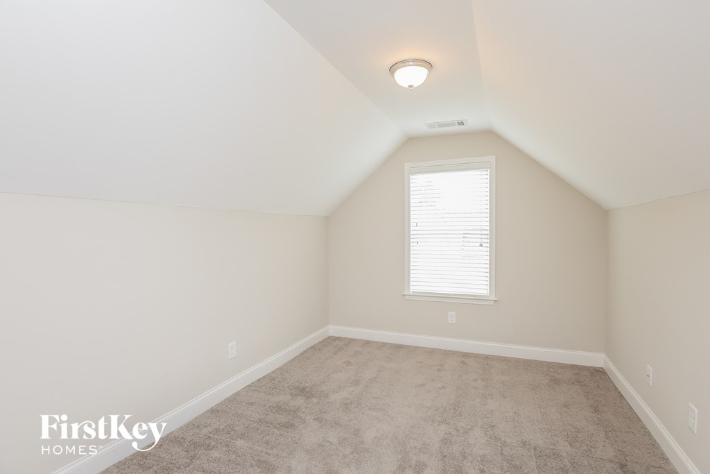 a bedroom with white walls and carpet and a window