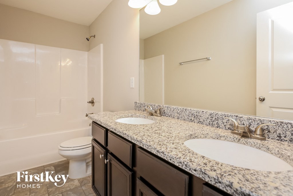 a bathroom with two sinks and a toilet and a shower