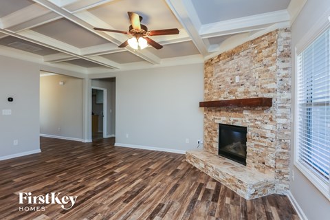 A room with a stone fireplace and a ceiling fan.