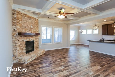 A spacious room with a stone fireplace and wooden flooring.