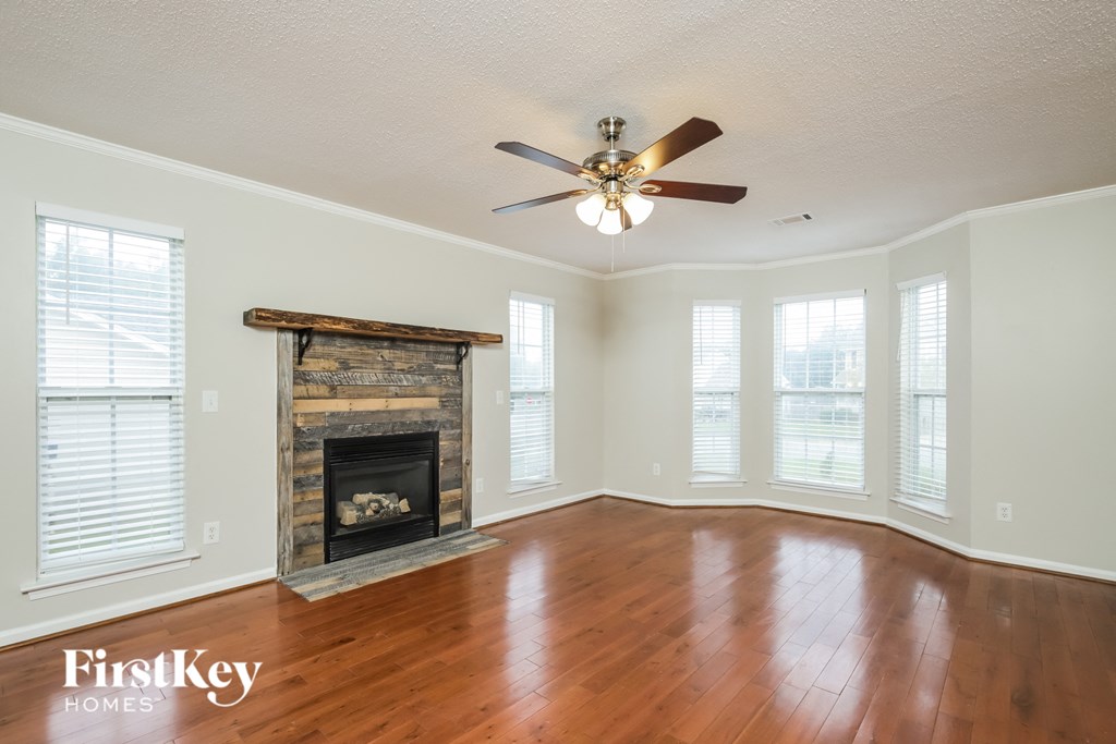 an empty living room with a fireplace and a ceiling fan