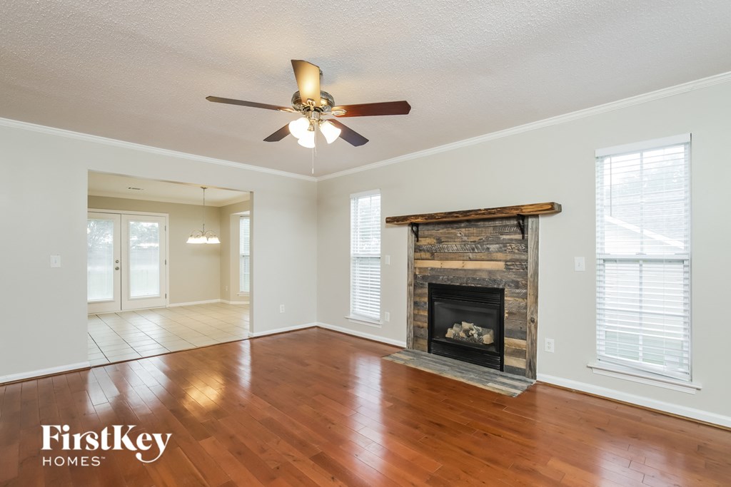 an empty living room with a fireplace and a ceiling fan