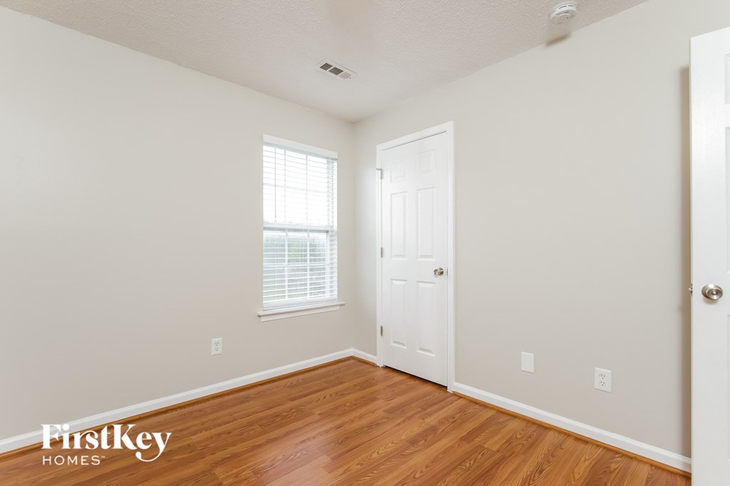 a bedroom with white walls and wood floors and a white door