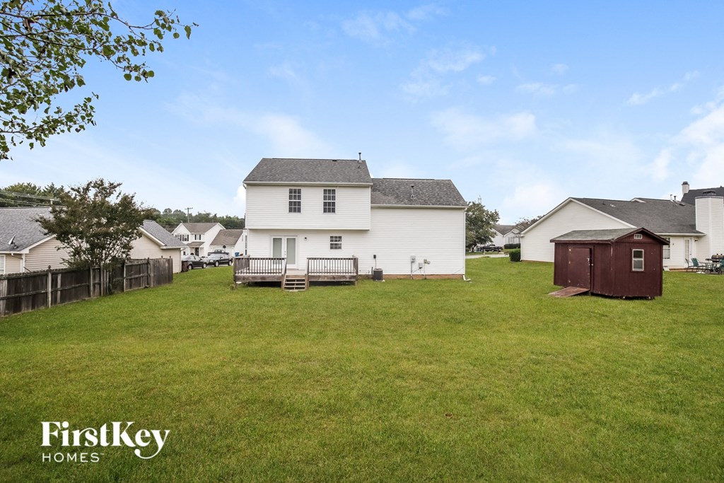 a backyard with a white house and a wooden shed
