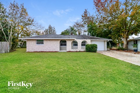 a small brick house with a lawn and a driveway