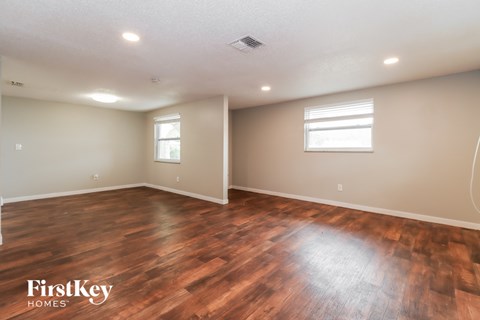 the spacious living room with hardwood flooring and a window