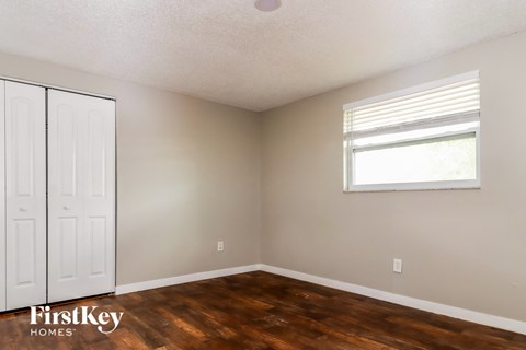 a bedroom with wood floors and a window and a white closet