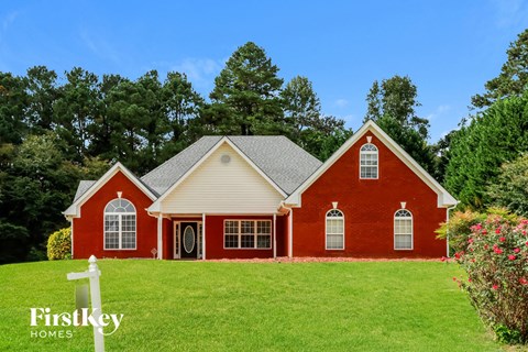 a red house with white trim on a green lawn
