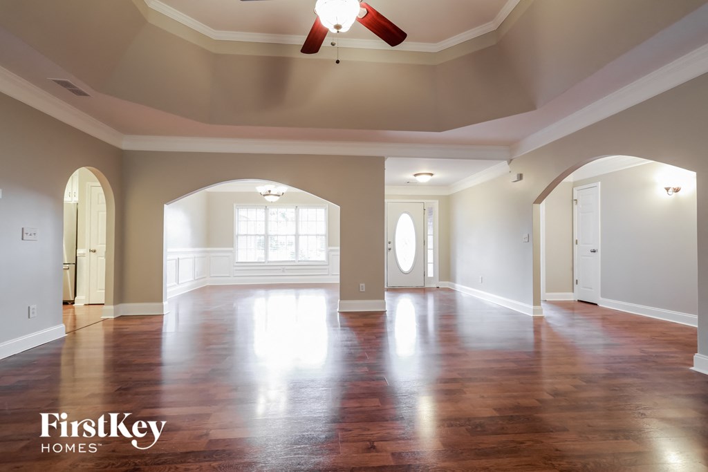 an empty living room with wood floors and a ceiling fan