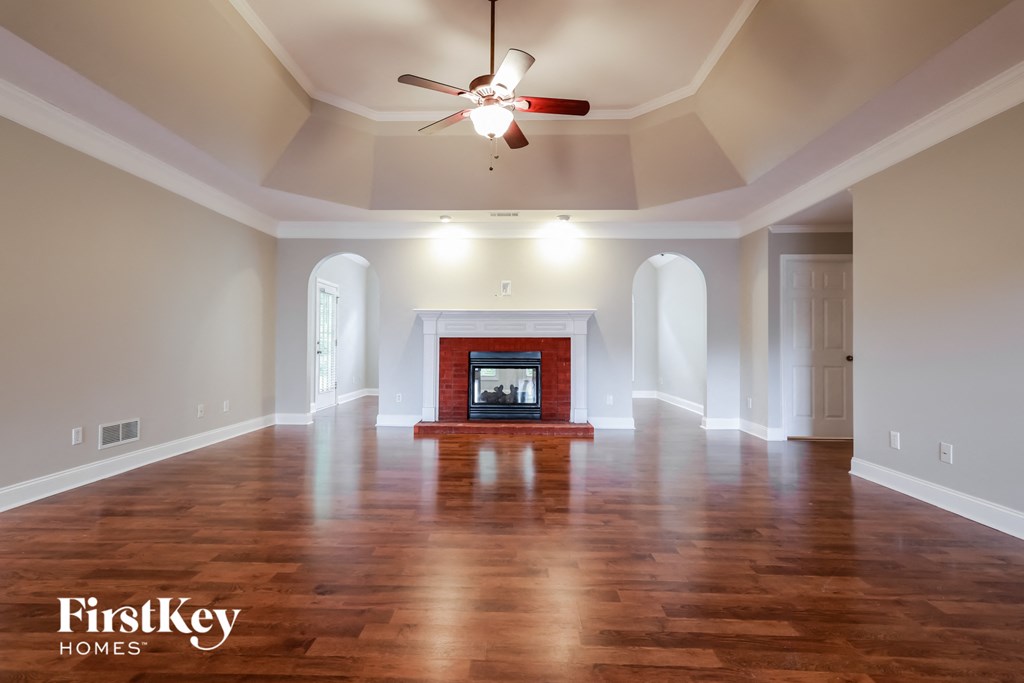 an empty living room with a fireplace and a ceiling fan