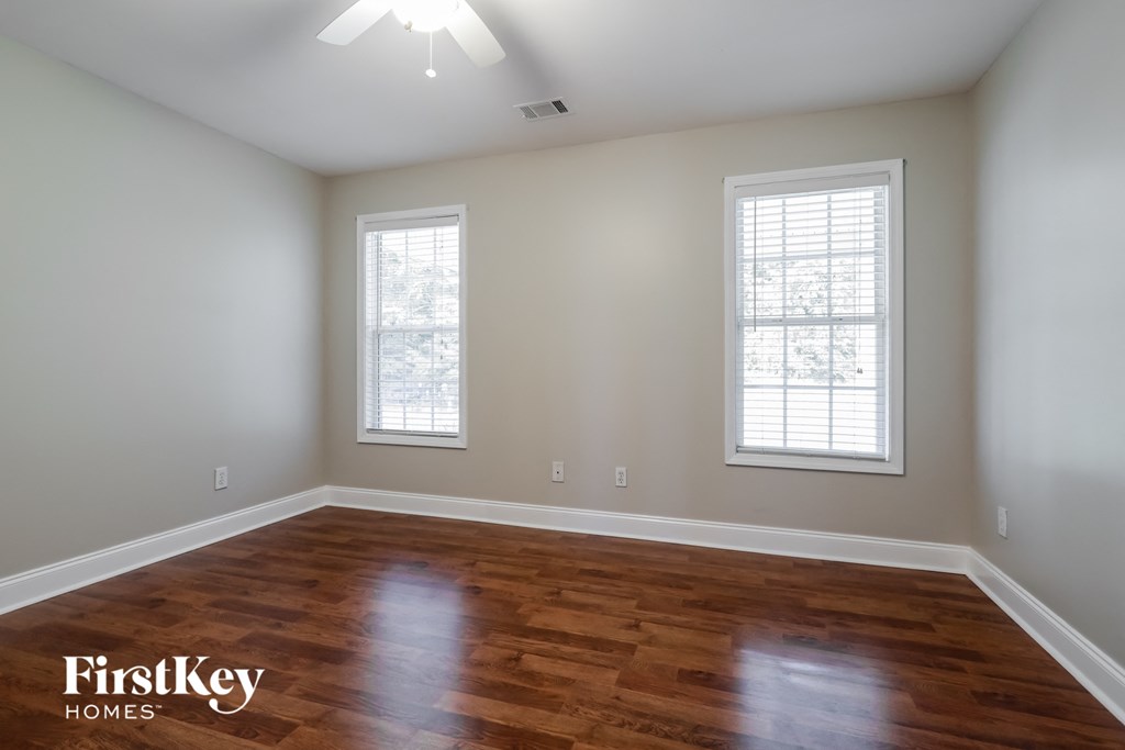 the second bedroom with hardwood flooring and two windows