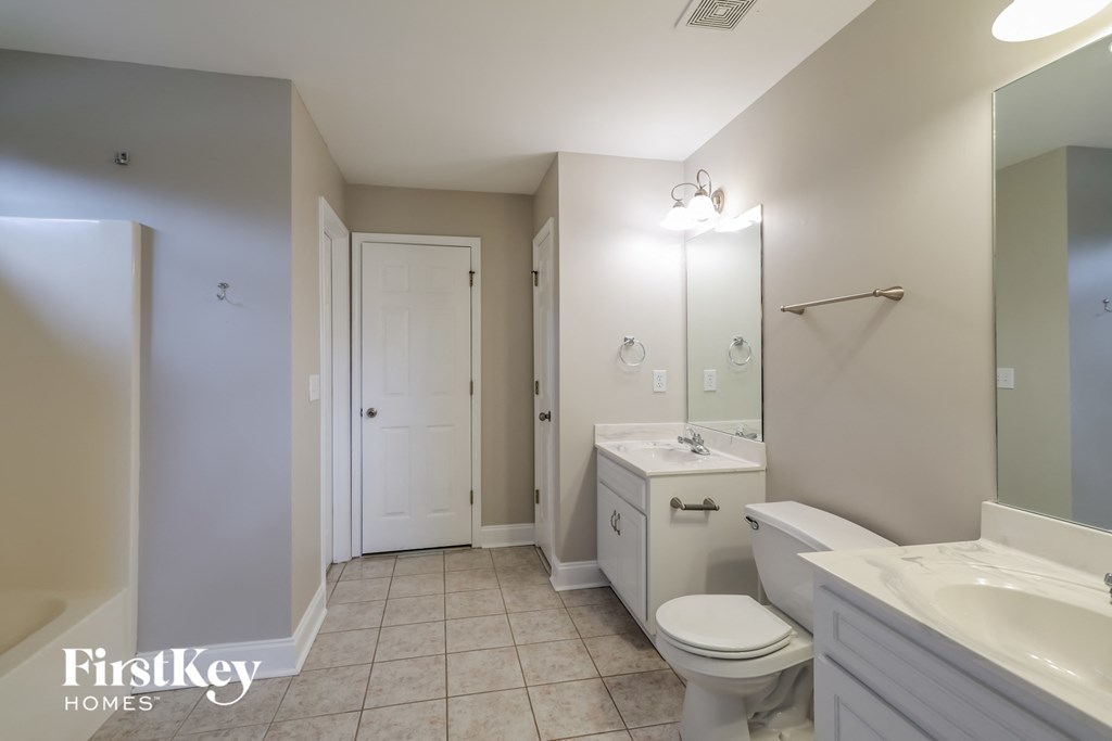 a white bathroom with a white toilet and sink and a mirror