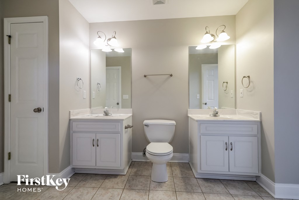 a white bathroom with a toilet and two sinks