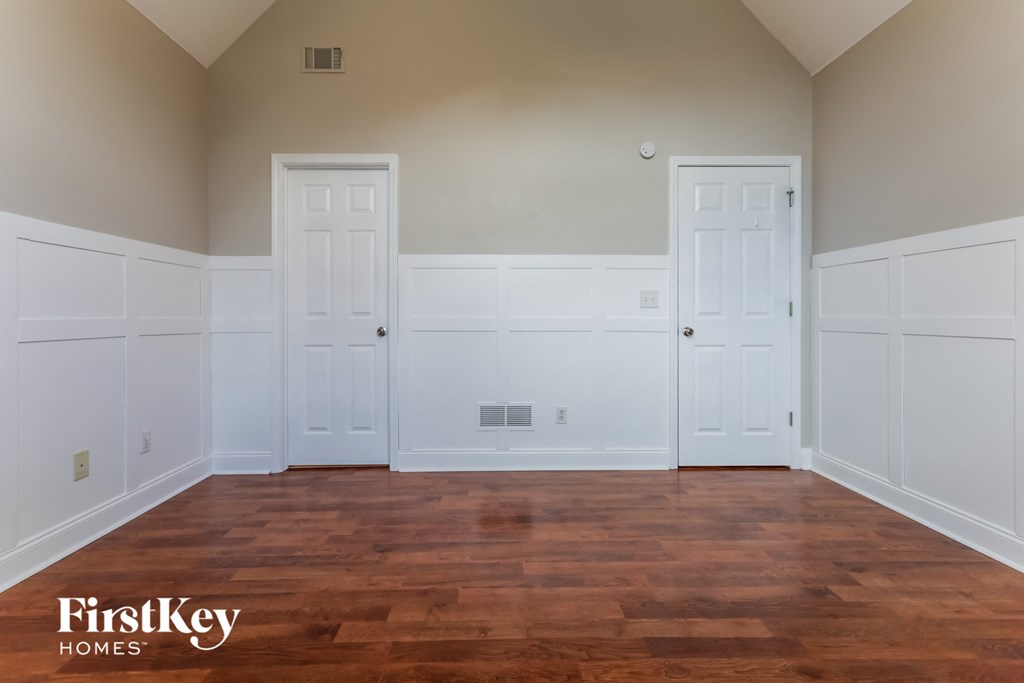a clean and empty room with white walls and wood floors