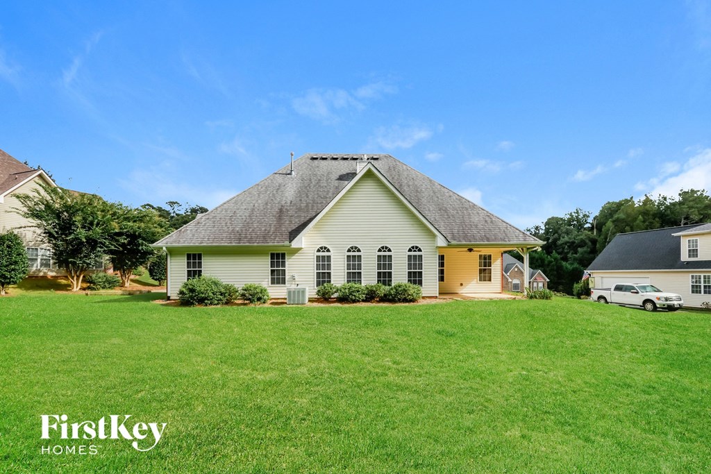 a yellow house with a gray roof on a green lawn