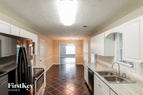 A kitchen with a black refrigerator and a sink.