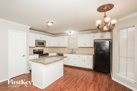 A kitchen with white cabinets and a black fridge.
