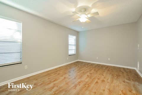 the spacious living room with hardwood floors and a ceiling fan