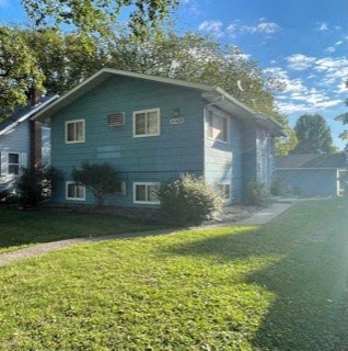 a blue house with a green lawn and a sidewalk