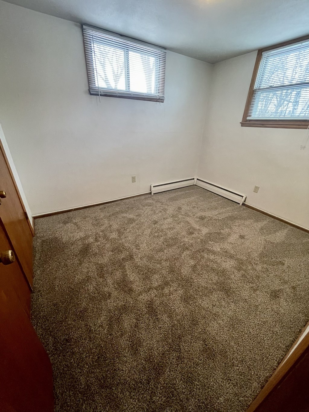an empty room with carpet and two windows