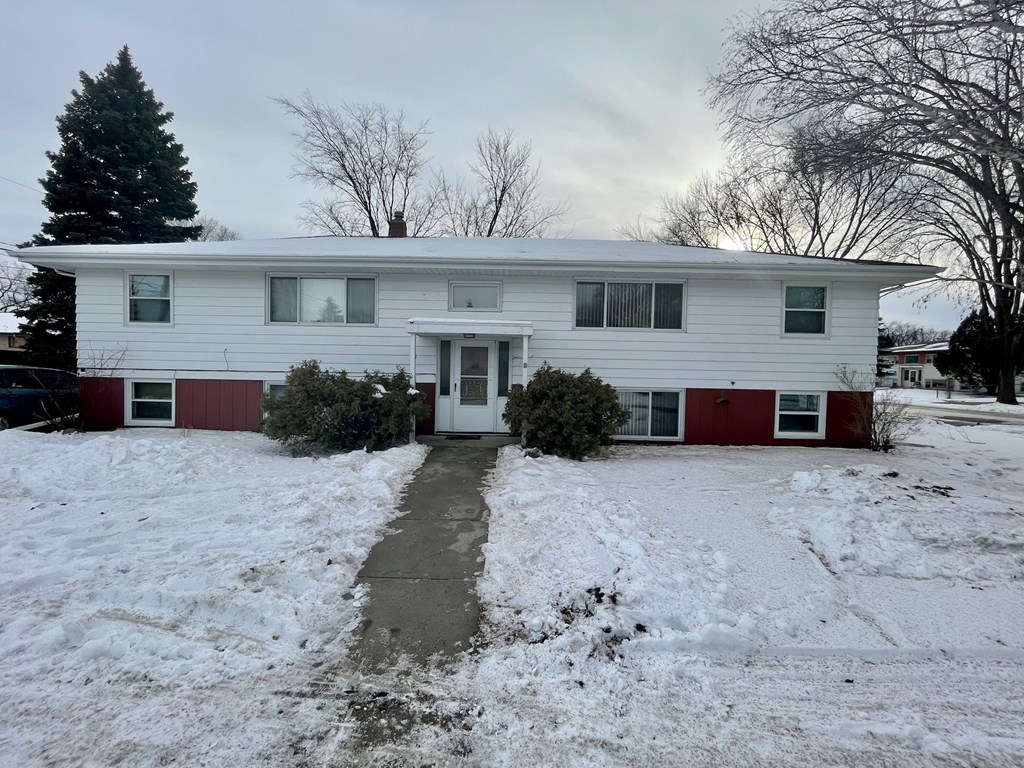 a white house with a red door and snow on the ground