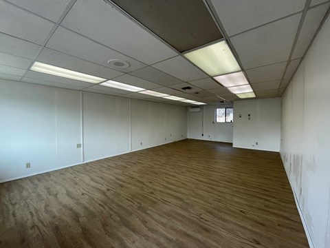 A room with wooden flooring and white walls.