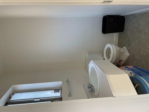 A bathroom with a toilet, sink, and a black device mounted on the wall.