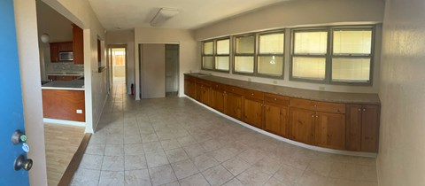 A long hallway with a blue door on the left and a kitchen area with a refrigerator and cabinets.
