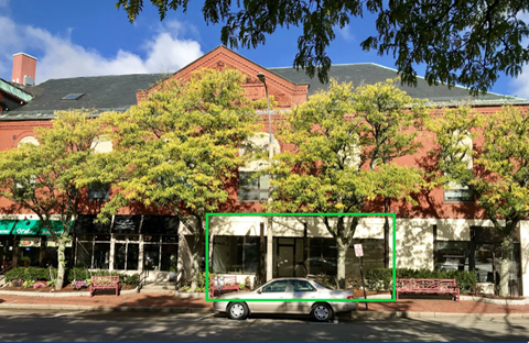 A car is parked in front of a building with a green awning.
