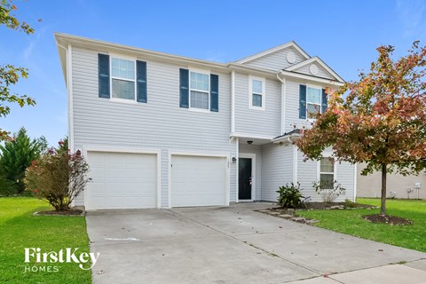 A two-story house with a garage and a tree in front.