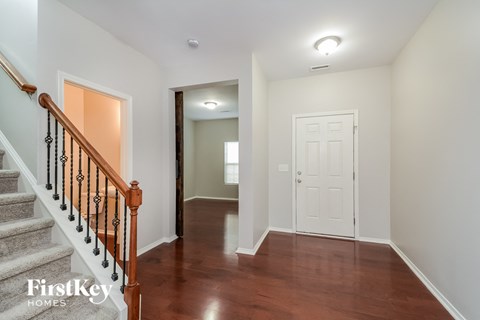A hallway with a wooden staircase and a white door.