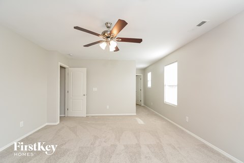 A spacious room with a ceiling fan and beige carpeting.