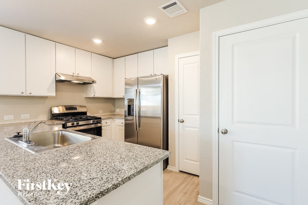 A kitchen with granite countertops and white cabinets.