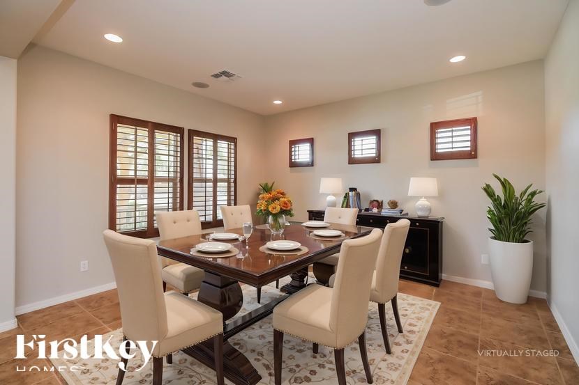 A dining room with a table set for six and a vase of flowers on the table.