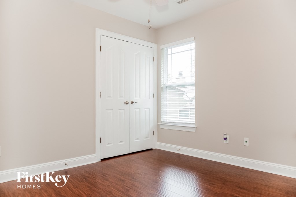 a bedroom with a door and a window and wood floors