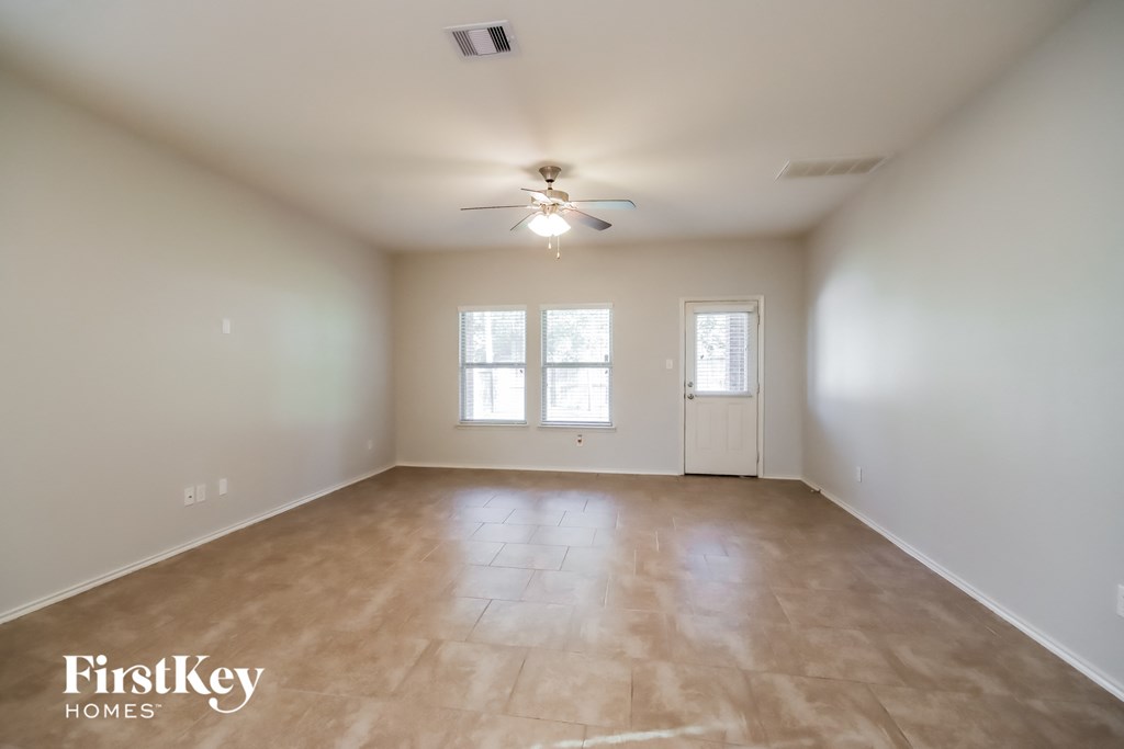 an empty living room with a ceiling fan and a window