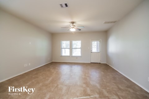 an empty living room with a ceiling fan and a window