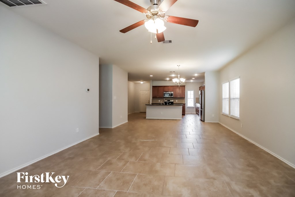 an empty living room and kitchen with a ceiling fan