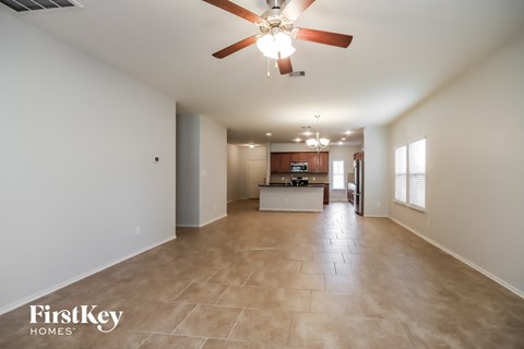 an empty living room and kitchen with a ceiling fan