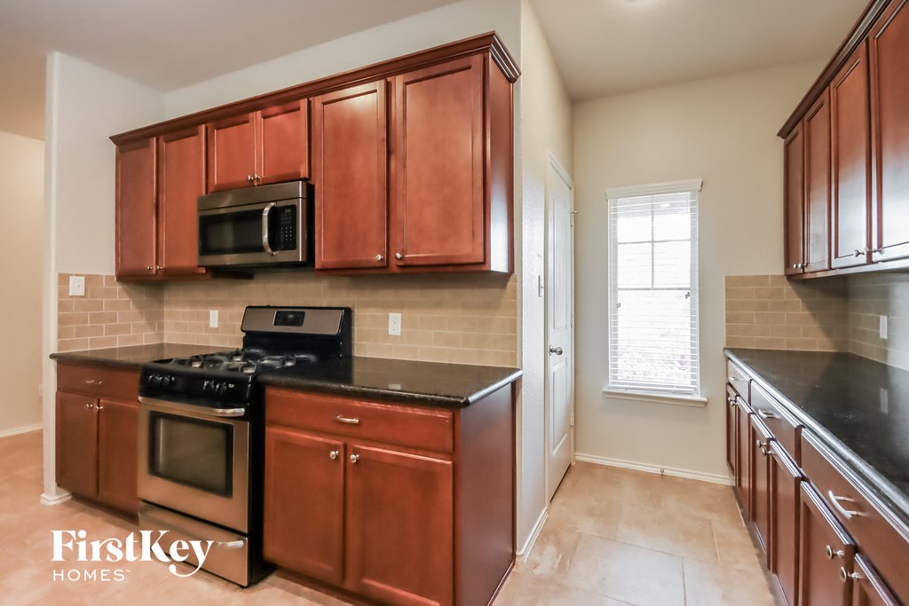 a kitchen with wood cabinets and black counter tops and a stove top oven