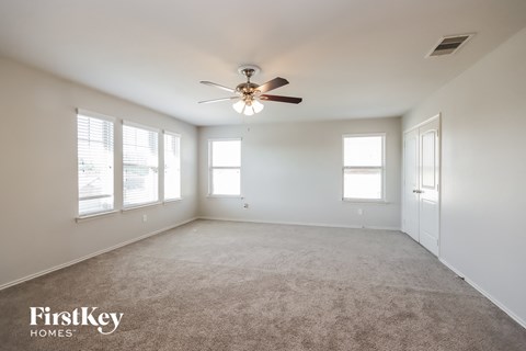 an empty living room with a ceiling fan and windows