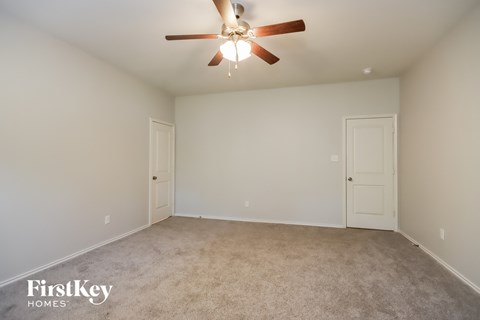 a empty living room with a ceiling fan and white doors