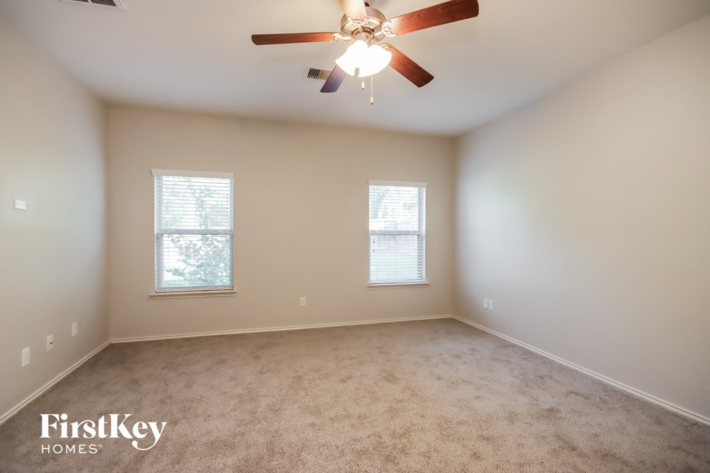 a carpeted room with a ceiling fan and two windows